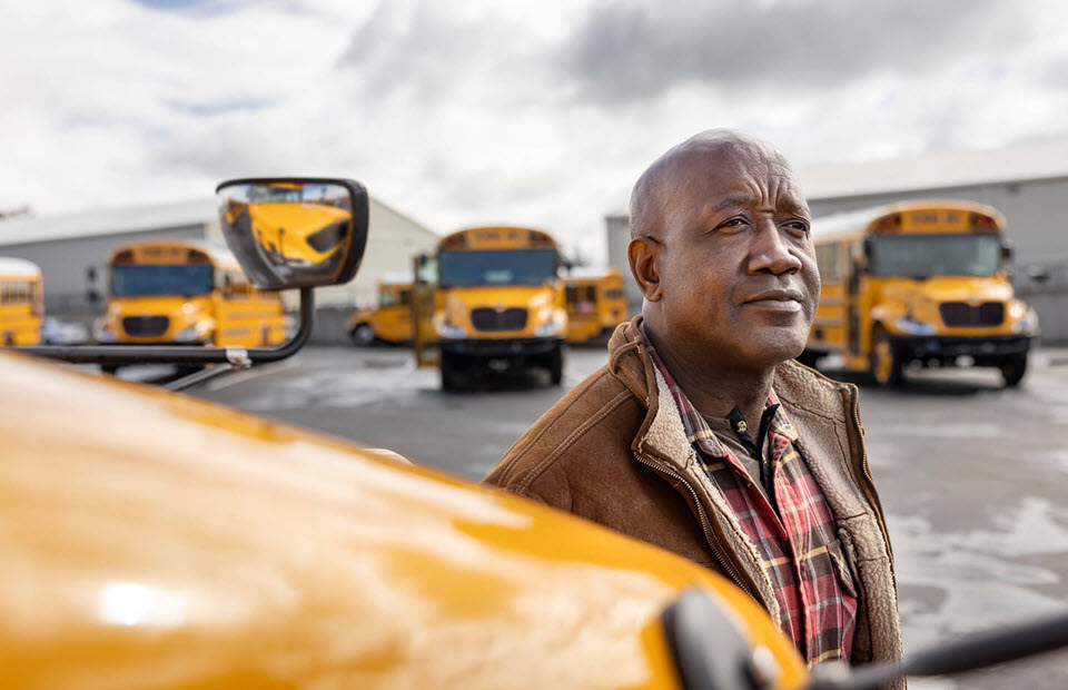 Man standing beside IC Bus CE Series hood with busses in background