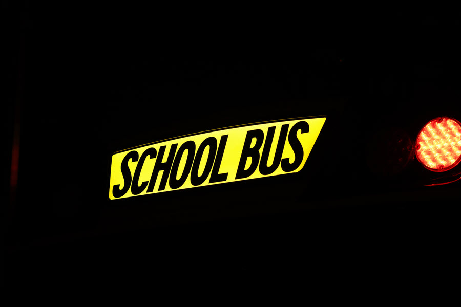 Illuminated school bus sign in dark setting