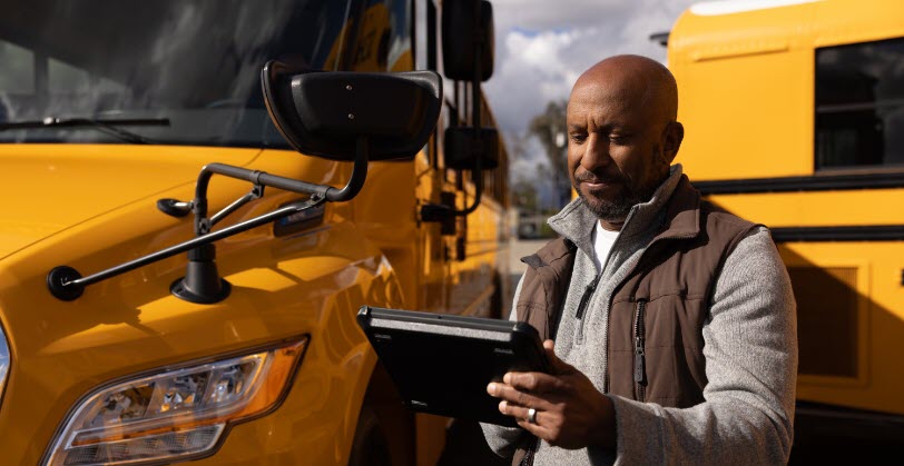 Man on tablet in front of school bus